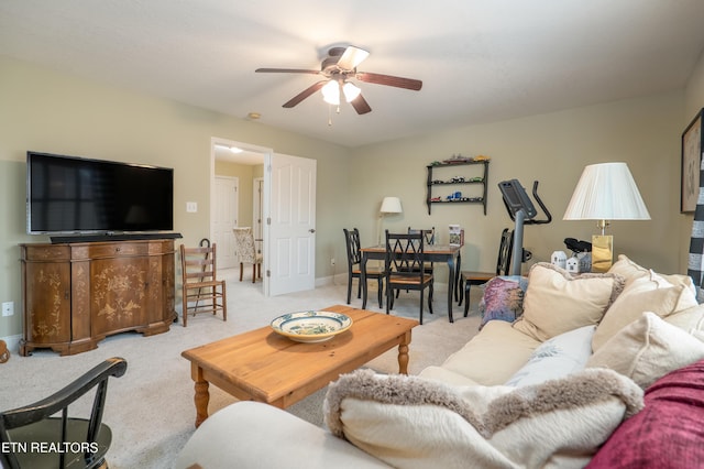 living room featuring baseboards, a ceiling fan, and light colored carpet