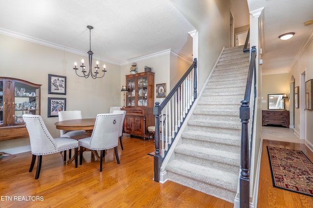 dining area featuring light wood-style floors, stairway, a chandelier, and crown molding