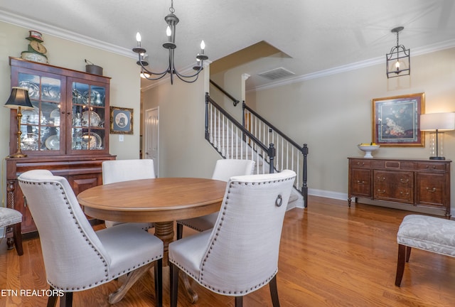 dining area with baseboards, wood finished floors, stairs, crown molding, and a chandelier