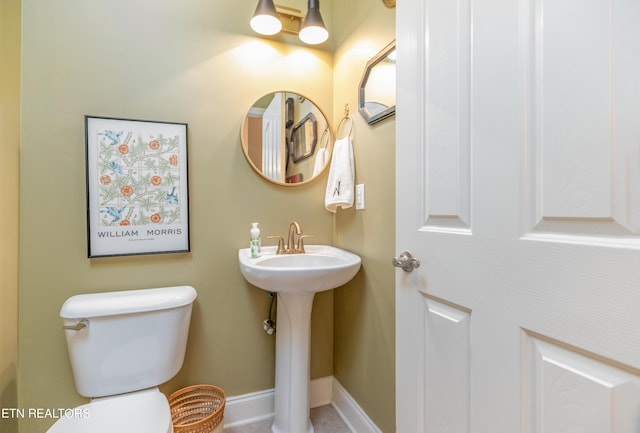 bathroom with toilet, baseboards, and a sink