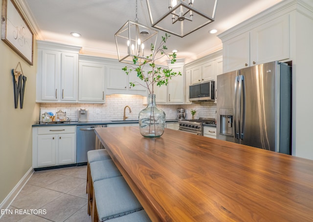 kitchen featuring light tile patterned floors, tasteful backsplash, appliances with stainless steel finishes, wooden counters, and a sink