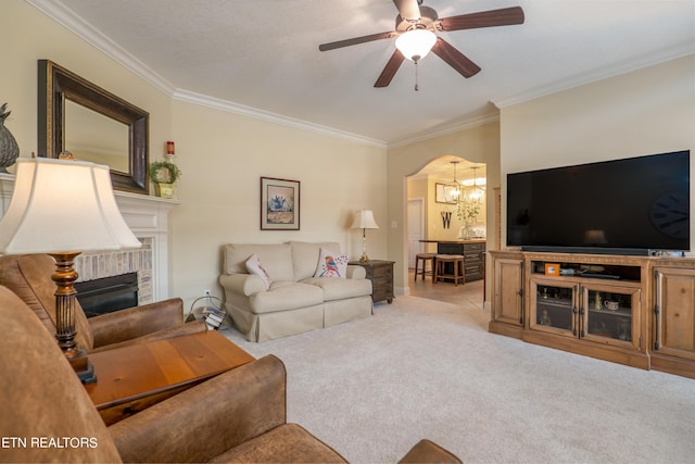 living area featuring arched walkways, carpet floors, a fireplace, and crown molding