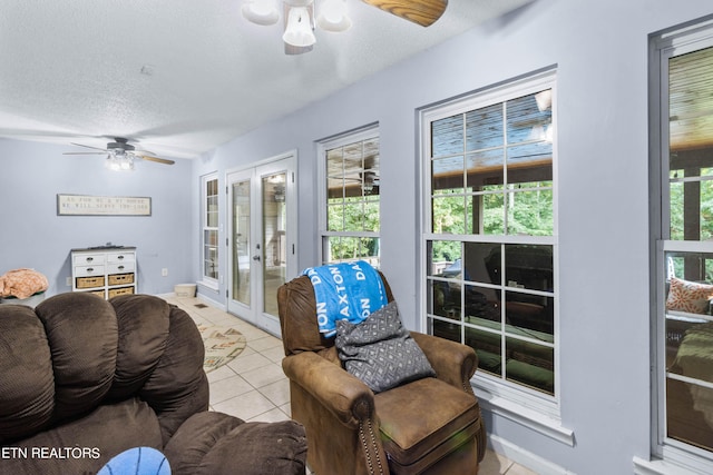 tiled living room featuring a textured ceiling, ceiling fan, and french doors