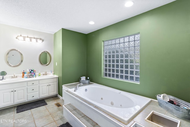 bathroom featuring a tub to relax in, tile patterned floors, a textured ceiling, and dual bowl vanity