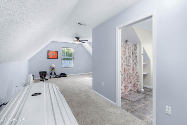 interior space with light carpet, a textured ceiling, lofted ceiling, and ceiling fan