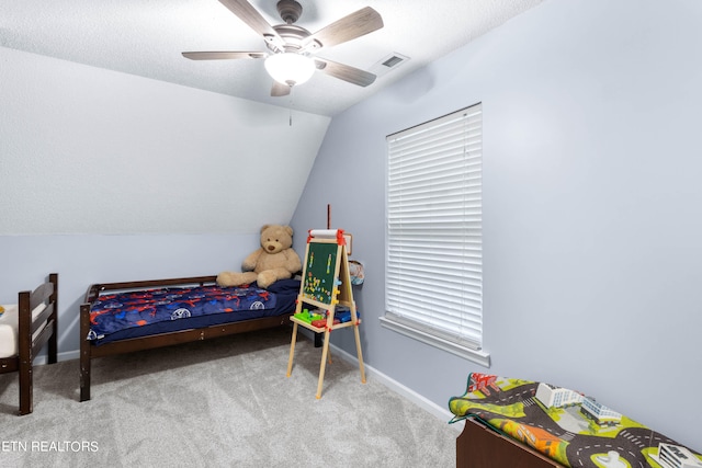 carpeted bedroom with a textured ceiling, vaulted ceiling, and ceiling fan