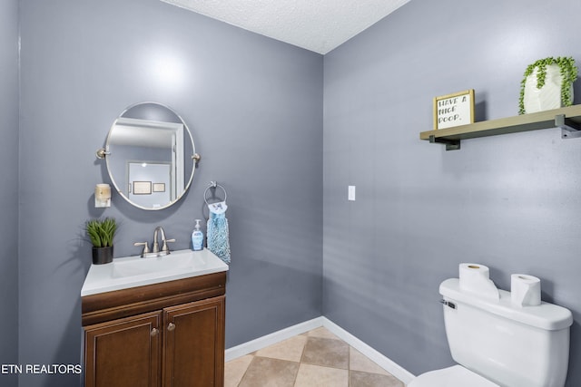 bathroom featuring tile patterned flooring, toilet, vanity, and a textured ceiling