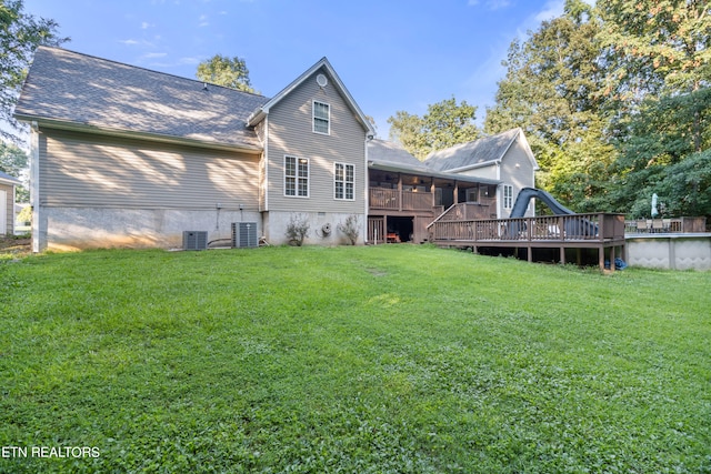 rear view of property with a deck, central AC unit, and a yard