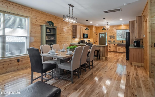 dining room with wood walls, light hardwood / wood-style flooring, and a wealth of natural light