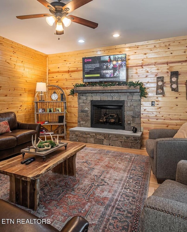 living room with a fireplace, wood walls, and ceiling fan