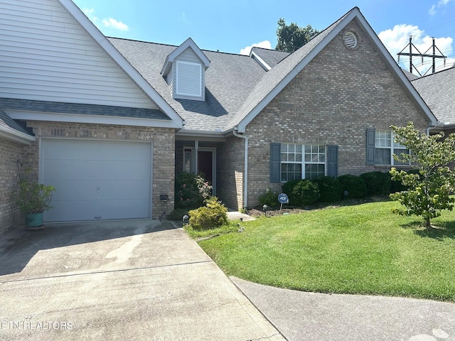 view of front of home featuring driveway, a garage, a shingled roof, a front yard, and brick siding