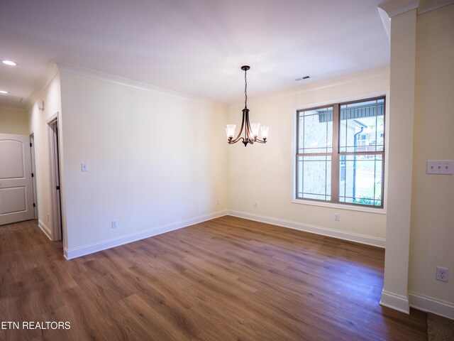 empty room with dark wood-type flooring, an inviting chandelier, and crown molding