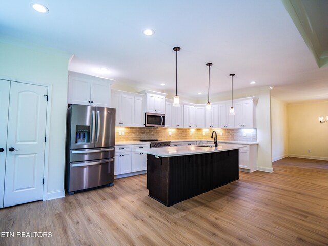 kitchen with appliances with stainless steel finishes, tasteful backsplash, light hardwood / wood-style flooring, and white cabinets