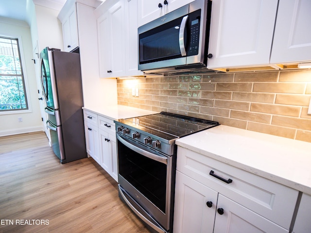 kitchen featuring backsplash, white cabinetry, appliances with stainless steel finishes, light stone counters, and light hardwood / wood-style floors