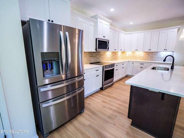 kitchen featuring sink, light hardwood / wood-style flooring, backsplash, and stainless steel appliances