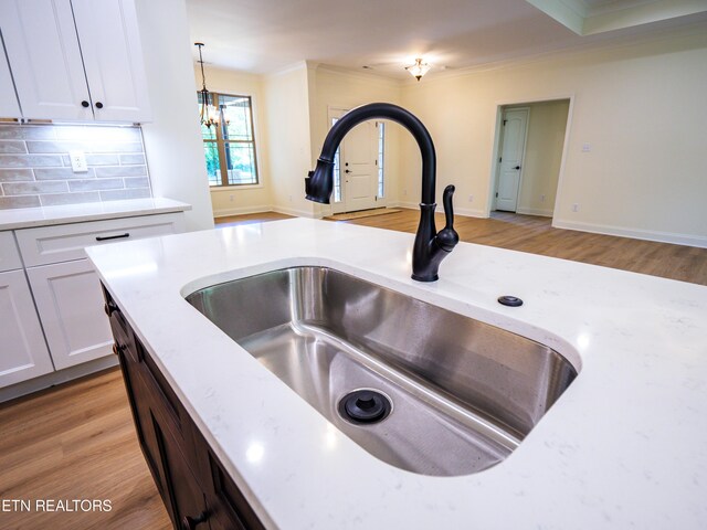 kitchen featuring sink, decorative light fixtures, white cabinetry, and light hardwood / wood-style floors