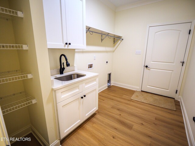 washroom with sink, electric dryer hookup, light hardwood / wood-style flooring, cabinets, and crown molding