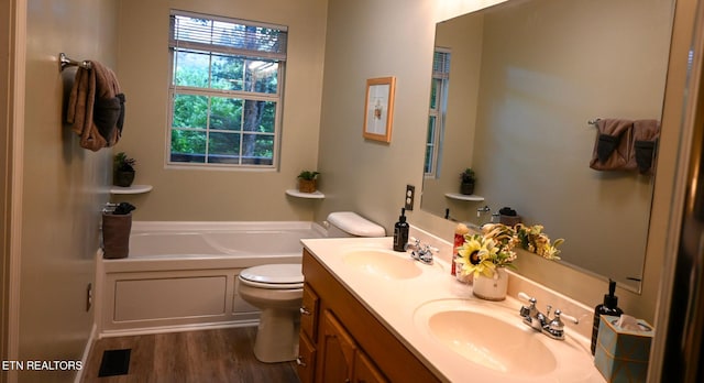 bathroom with hardwood / wood-style floors, double vanity, a bathing tub, and toilet