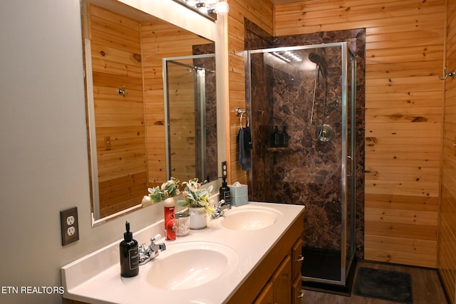 bathroom featuring walk in shower, wood-type flooring, double vanity, and wooden walls