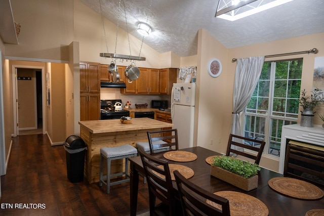 kitchen featuring a textured ceiling, black appliances, lofted ceiling with skylight, and dark hardwood / wood-style floors