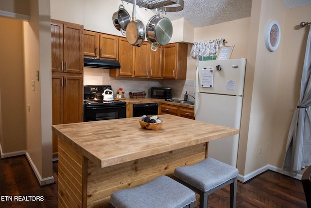 kitchen with black appliances, backsplash, dark hardwood / wood-style floors, a textured ceiling, and a kitchen breakfast bar