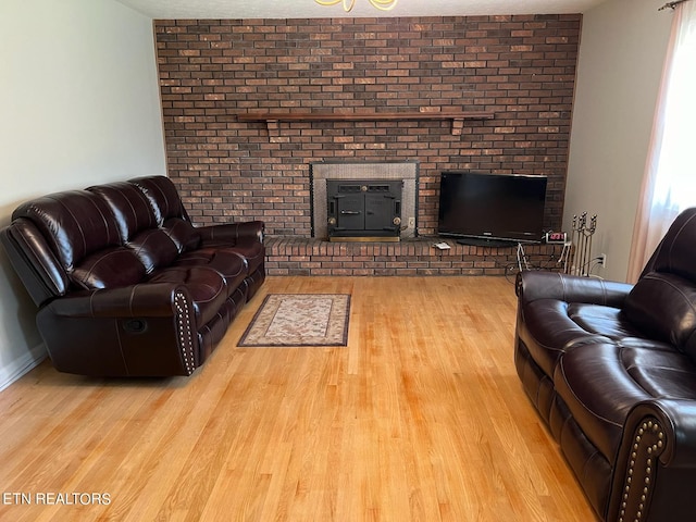 living room with brick wall, a fireplace, and light hardwood / wood-style flooring