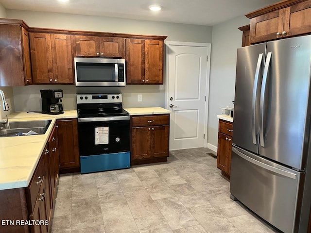 kitchen featuring appliances with stainless steel finishes, light tile patterned floors, and sink