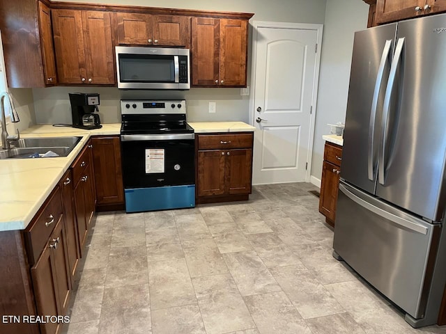 kitchen featuring light tile patterned floors, appliances with stainless steel finishes, and sink