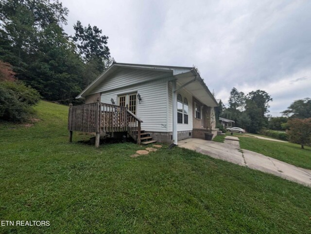 view of side of home featuring a wooden deck and a lawn