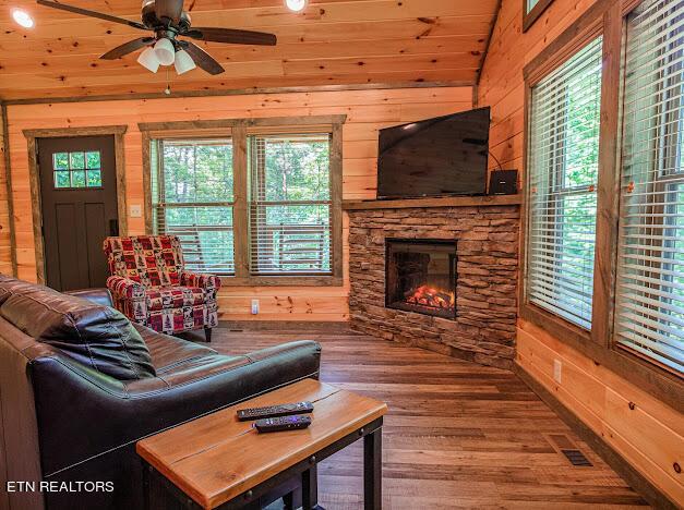 living room featuring a fireplace, wood finished floors, visible vents, and wooden walls