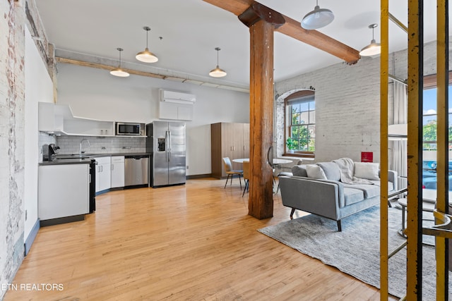 kitchen with tasteful backsplash, decorative light fixtures, light hardwood / wood-style flooring, white cabinetry, and appliances with stainless steel finishes