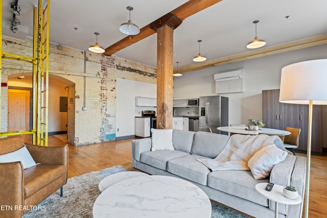 living room featuring electric panel, wood walls, beam ceiling, light wood-type flooring, and a wall mounted air conditioner