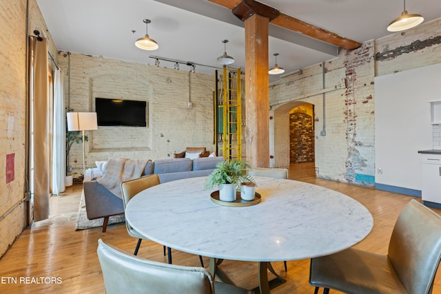 dining area with light hardwood / wood-style flooring, beamed ceiling, and track lighting