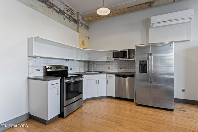 kitchen with sink, white cabinetry, decorative backsplash, light hardwood / wood-style flooring, and appliances with stainless steel finishes