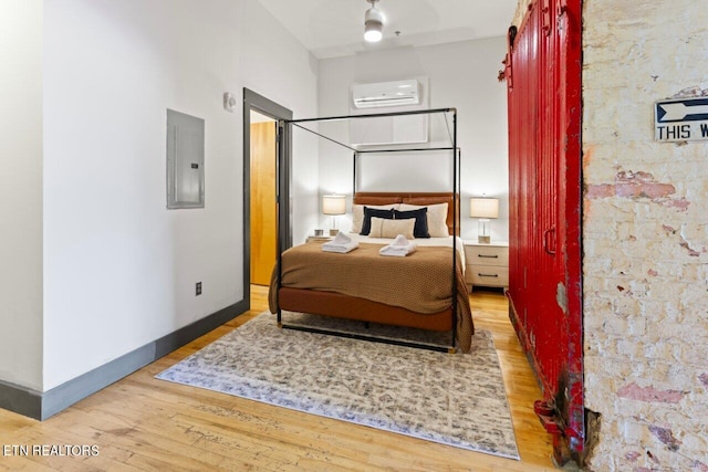 bedroom with electric panel, hardwood / wood-style flooring, and a wall mounted air conditioner