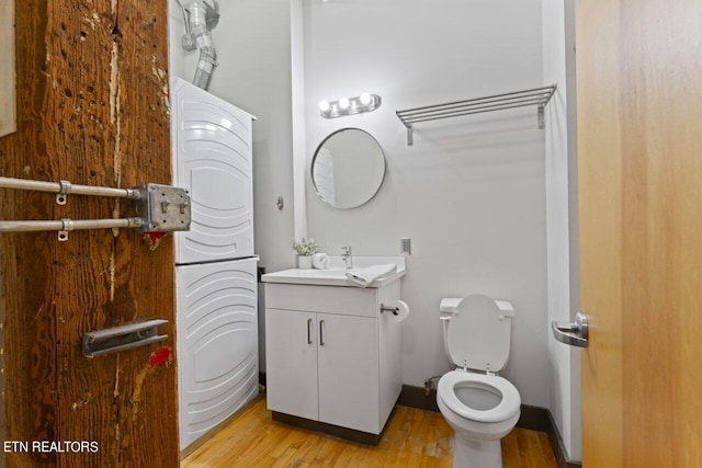 bathroom with vanity, toilet, washer / dryer, and hardwood / wood-style flooring