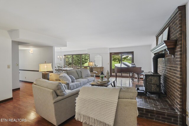 living room featuring a wood stove, a chandelier, and hardwood / wood-style flooring