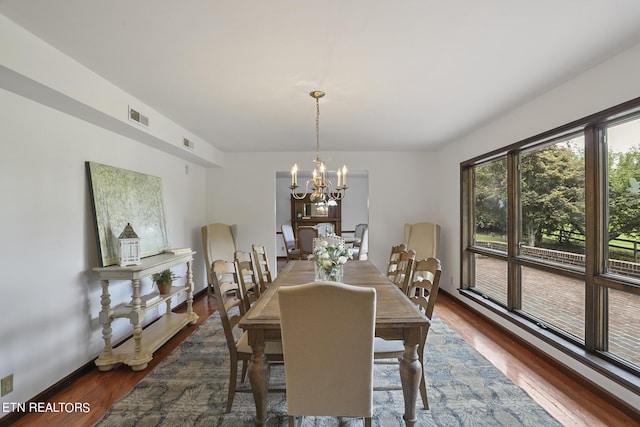 dining area with dark wood-type flooring and a chandelier