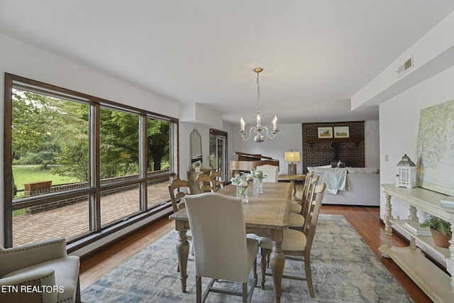 dining space with wood-type flooring, a baseboard heating unit, and an inviting chandelier