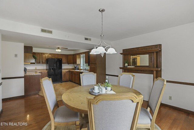 dining room with ceiling fan with notable chandelier and dark hardwood / wood-style floors