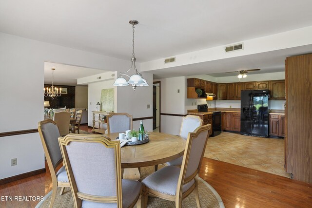 dining room featuring ceiling fan with notable chandelier and light hardwood / wood-style floors