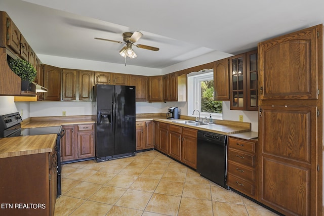 kitchen with light tile patterned flooring, sink, ceiling fan, black appliances, and wall chimney exhaust hood