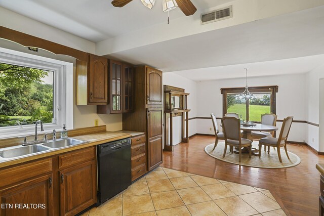 kitchen with sink, hanging light fixtures, black dishwasher, ceiling fan with notable chandelier, and light wood-type flooring