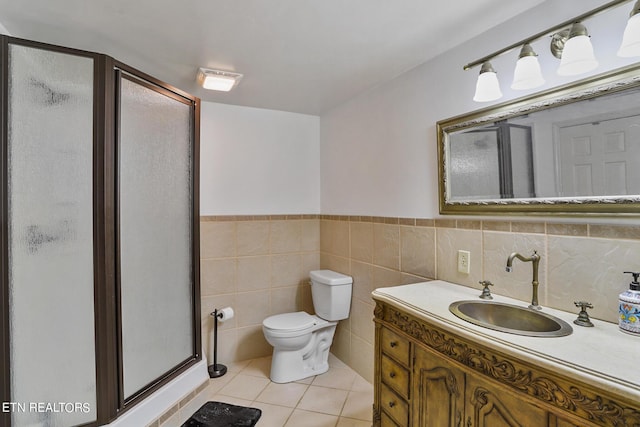 bathroom with toilet, an enclosed shower, tile walls, vanity, and tile patterned flooring