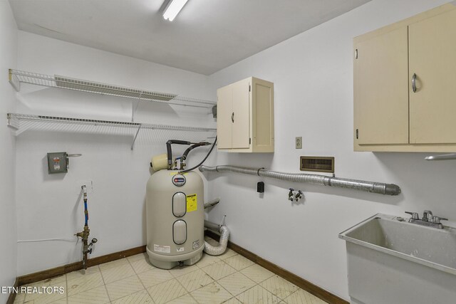 laundry room featuring electric water heater, sink, and cabinets