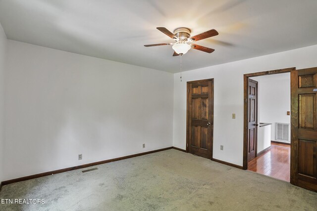 empty room featuring ceiling fan and light carpet