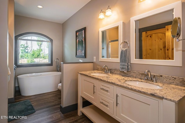 bathroom with a bathtub, toilet, wood-type flooring, and double vanity