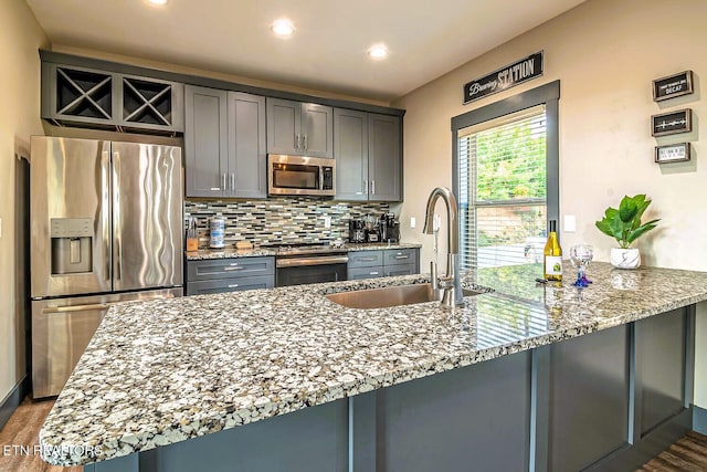 kitchen with hardwood / wood-style flooring, backsplash, appliances with stainless steel finishes, and kitchen peninsula