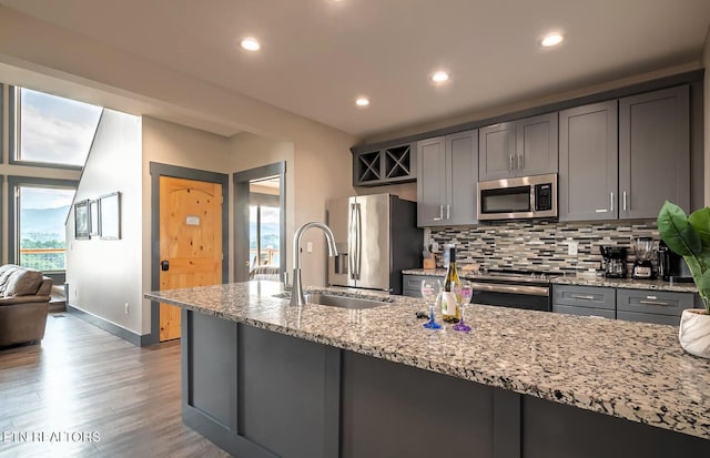 kitchen with appliances with stainless steel finishes, a wealth of natural light, decorative backsplash, and light wood-type flooring