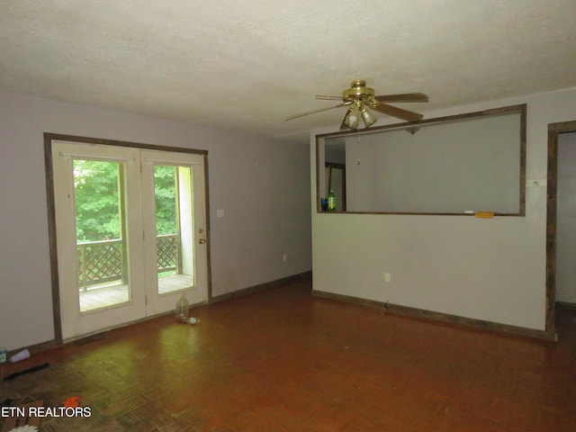 empty room with a textured ceiling, ceiling fan, and baseboards